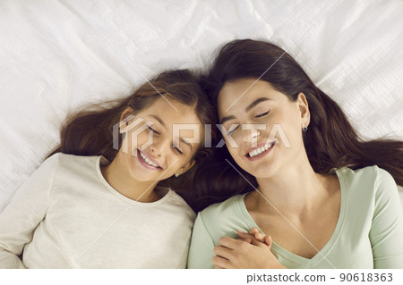 Happy beautiful young mother and her child sleeping on a comfortable bed together 90618363