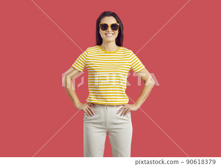 Happy smiling woman in casual outfit and sunglasses standing isolated on red background 90618379