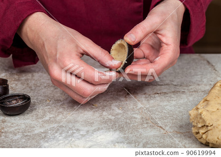 A small portion of the dough is stacked in a metal nut mold for baking A small portion of the dough is stacked in a metal nut mold for baking 90619994
