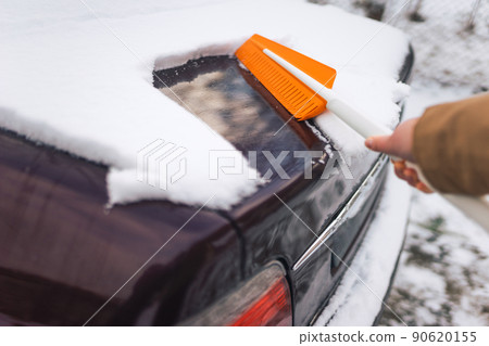 Person cleans the body of a car from wet snow Person cleans the body of a car from wet snow 90620155
