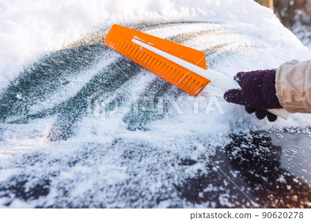 Cleaning the car from snow with a modern rubber brush 90620278