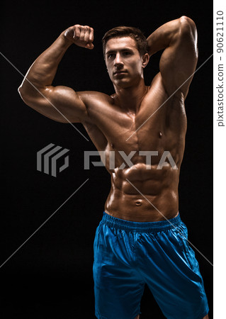 Muscular and fit young bodybuilder fitness male model posing over black background. 90621110