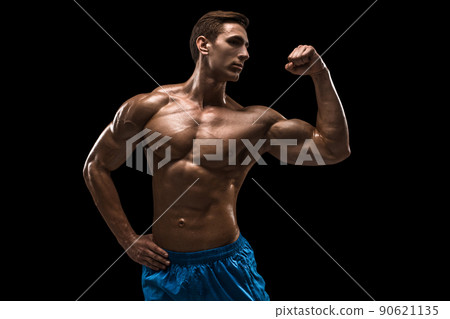 Muscular and fit young bodybuilder fitness male model posing over black background. 90621135