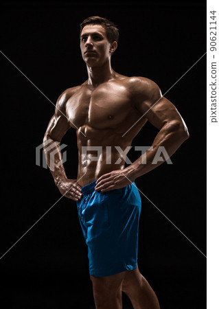 Muscular and fit young bodybuilder fitness male model posing over black background. 90621144