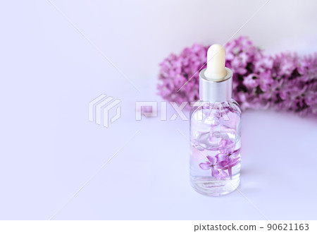 Closeup of glass dropper bottle with pipette with serum and lilac flowers. Essential oil, natural beauty cosmetics, bio science and research, skin care concept. Macro. Front view, high angle shot 90621163
