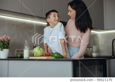 Portrait shot pf beautiful mother and little con looking at each other in kitchen. 90621170
