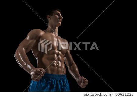 Muscular and fit young bodybuilder fitness male model posing over black background. Muscular and fit young bodybuilder fitness male model posing over black background. 90621223
