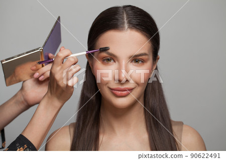 Makeup concept. Woman makeup artist applies make-up to a beautiful female model face Makeup concept. Woman makeup artist applies make-up to a beautiful female model face 90622491