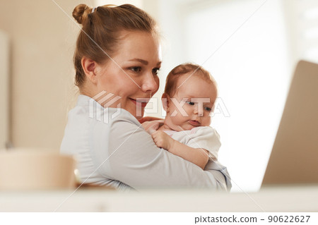 Young smiling mother showing her baby to grandmother who is calling them through Skype Young smiling mother showing her baby to grandmother who is calling them through Skype 90622627