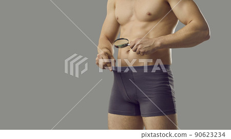 Background with man looking through magnifying glass inside his underpants at his penis 90623234