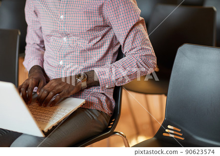 Close-up of unrecognizable Black man with wristwatch sitting on chair and composing business article on laptop Close-up of unrecognizable Black man with wristwatch sitting on chair and composing business article on laptop 90623574