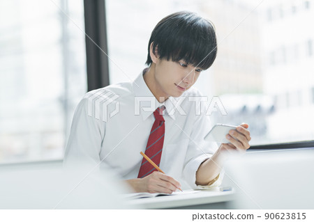 男高中生在教室裡看智能手機 90623815