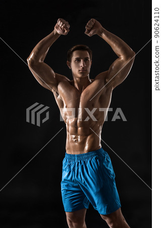 Muscular and fit young bodybuilder fitness male model posing over black background. Muscular and fit young bodybuilder fitness male model posing over black background. 90624110