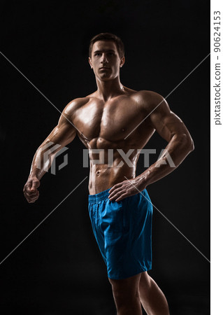 Muscular and fit young bodybuilder fitness male model posing over black background. Muscular and fit young bodybuilder fitness male model posing over black background. 90624153