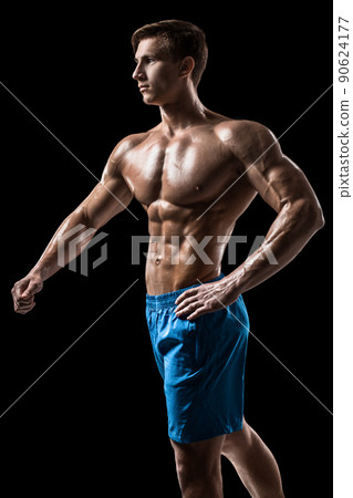 Muscular and fit young bodybuilder fitness male model posing over black background. Muscular and fit young bodybuilder fitness male model posing over black background. 90624177