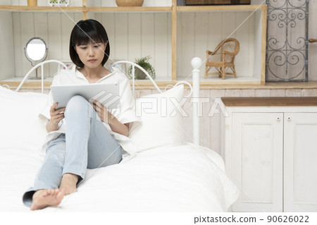 Young woman sitting in bed and looking at a tablet 90626022