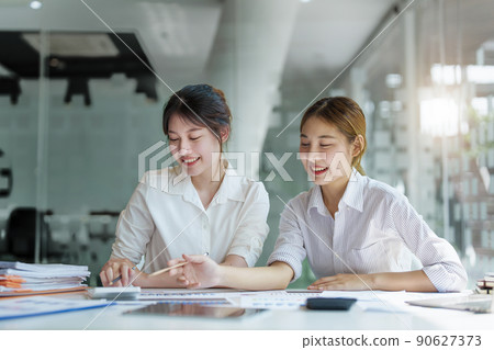 Negotiation, Analysis, Discussion, Portrait of an Asian young economist and marketer pointing to a financial data sheet to plan investments to prevent risks and losses for the company 90627373