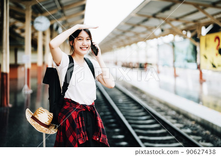 summer, relax, vacation, travel, portrait of beautiful Asian girl using the smartphone mobile to call friends at the train station while waiting for their travel time 90627438