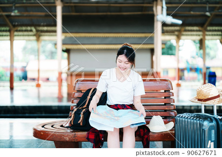 summer, relax, vacation, travel, portrait of a cute Asian girl looking at a map to plan a trip while waiting at the train station 90627671