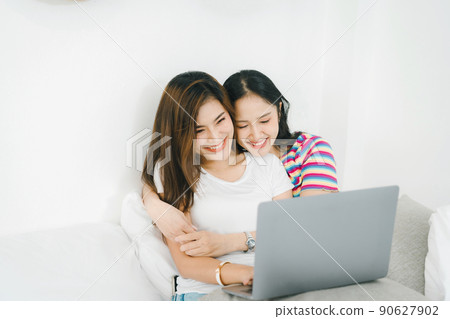 lgbtq, lgbt concept, homosexuality, portrait of two asian women posing happy together and loving each other while playing computer laptop on bed. 90627902