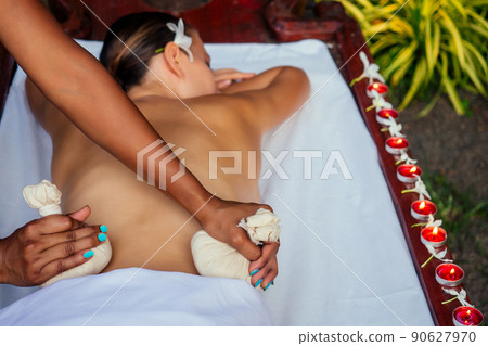 Portrait of young beautiful woman lying on a wooden table in spa environment flowers and candles Portrait of young beautiful woman lying on a wooden table in spa environment flowers and candles 90627970