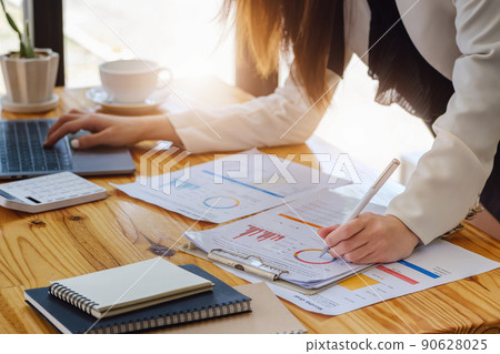 Young economists or accountants or financiers and investors are reviewing budget documents and using computers to study impact and risk assessments on corporate investment management 90628025