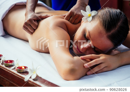 Ayurveda indian woman having relaxing body asia spa treatment india flowers and candles 90628026