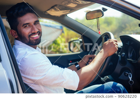 travel vacation happy indian man in white shirt collar buying new car and showing the key, sitting in car on beach sea india octan Goa .a trip to the beach in car 90628220