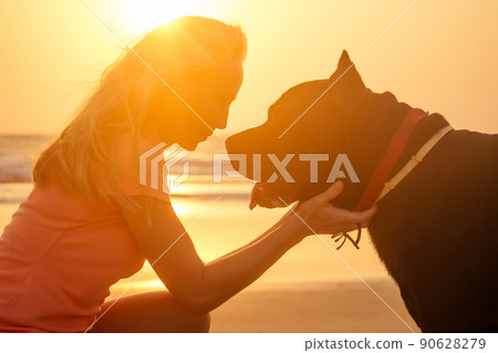 Blonde smiling young woman hugging her Cane Corso dog on the beach 90628279