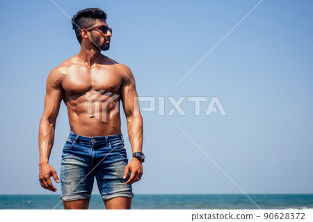 portrait of happy young african man on the beach.Handsome and confident Masculine hard fitness model male body bodybuilder with six pack.India trainer with perfect abs, shoulders,biceps, triceps,chest 90628372