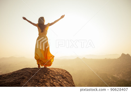 Woman inyellow silk long train dress in MAatanga hills in Hampi karnataka India 90628407