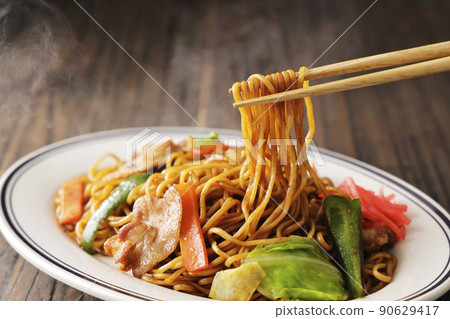 用筷子提起的帶有噝噝作響的醬汁的炒麵 用筷子提起的帶有噝噝作響的醬汁的炒麵 90629417