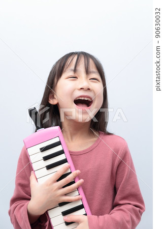 Girl playing keyboard harmonica 90630032