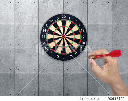hand holding darts arrow. target for Darts. Concrete wall background. concept marketing target 90632151