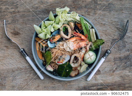 Spicy Stir Fried seafood Instant Noodles with herbs with various spices served with vegetables in ceramic plate. 90632475