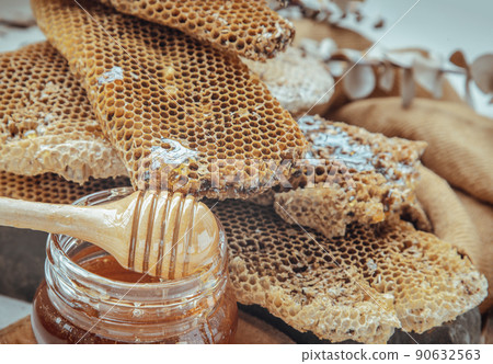 Close-up of Fresh honeycombs with Wooden honey dipper stick on honey glass jar. 90632563