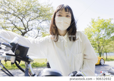 Bike girl image: A young woman straddling a motorcycle wearing a mask 90632692