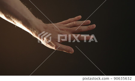 man hand playing with sun light on a black background man hand playing with sun light on a black background 90635632