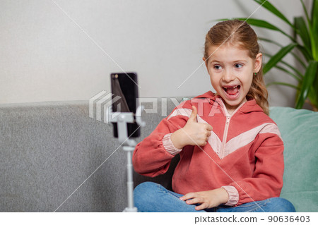 Small blonde blogger girl, an influential person, communicates with subscribers, conducts a live broadcast with a cat, looks at the smartphone screen at home. When taking a selfie, call your friends. 90636403