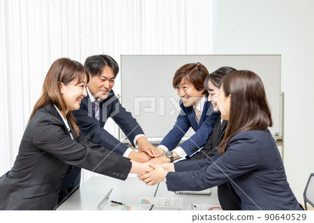 Men and women in suits having business talks in the conference room (contract / handshake) Men and women in suits having business talks in the conference room (contract / handshake) 90640529