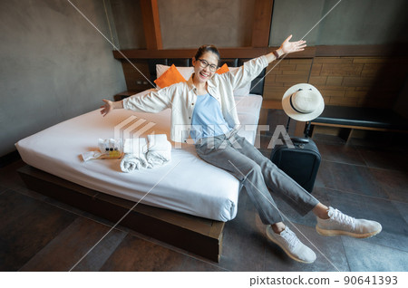 Happiness Asian tourist sitting on bed in hotel bedroom after check in. Conceptual of travel and accommodation. 90641393