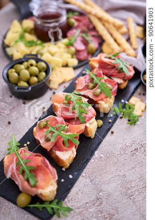 bruschetta with prosciutto ham and capers with traditional antipasto meat plate on background 90641903