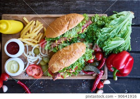 BBQ hot dog served with vegetables and French fries and sauces on wooden serving board 90641916