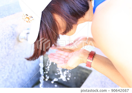 一名婦女在公園的供水服務中洗臉 一名婦女在公園的供水服務中洗臉 90642087