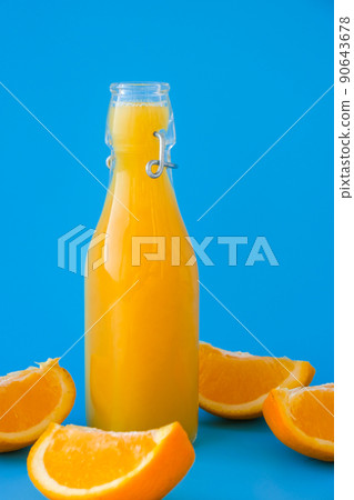 Glass bottle of fresh squeezing Orange juice with sliced fruits on blue background. Fruit juice, fresh cold drink. Refreshment in summer. Fruits cut in half Glass bottle of fresh squeezing Orange juice with sliced fruits on blue background. Fruit juice, fresh cold drink. Refreshment in summer. Fruits cut in half 90643678
