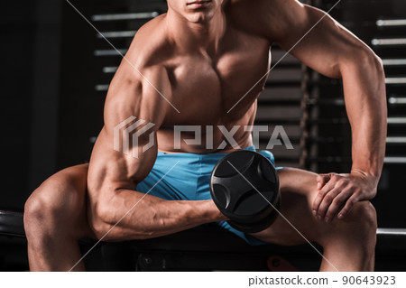 Very power athletic guy bodybuilder execute exercise with dumbbells at dark gym 90643923