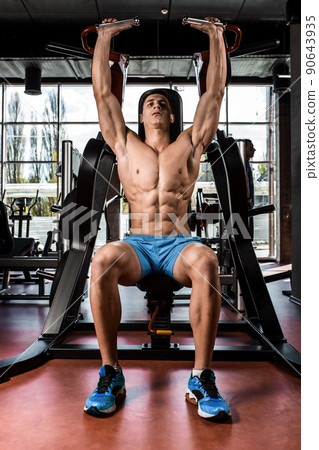 Tense muscles of hands under load. Man doing exercise for biceps in the gym. Tense muscles of hands under load. Man doing exercise for biceps in the gym. 90643935