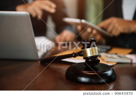 Justice and law concept.Male judge team in a courtroom the gavel, working with digital tablet computer on wood table. 90643970