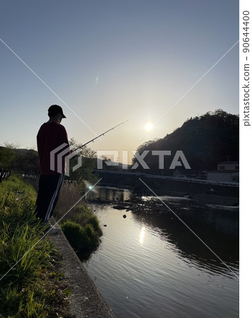 晚上在河邊釣魚的男孩 晚上在河邊釣魚的男孩 90644400