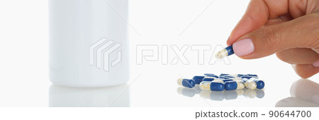 Female take one blue jelly capsule from bunch on surface 90644700
